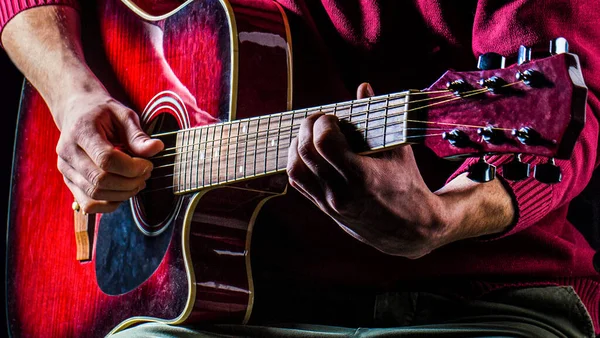 Een man die gitaar speelt, met een akoestische gitaar in zijn handen. Muziekconcept. Mannelijke gitarist speelt — Stockfoto