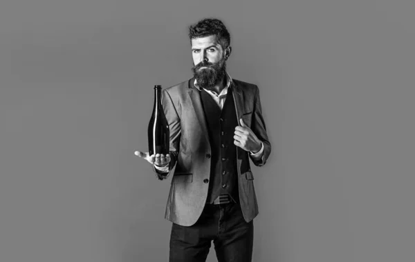 Stylish male in tuxedo, suit, jacket. Space for text. Man holding bottle with champagne, wine. Bearded man with a bottle champagne of and glass. Black and whit