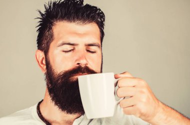 Sabah konsepti. Yakışıklı sakallı erkek elinde kahve ve çay tutuyor. Bir fincan taze kahveyle gülümseyen hippi. Sakallı adam gülümsüyor.