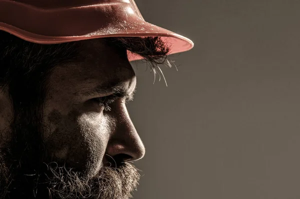 Een man met een baard in een helm of hoed. Portret architect bouwer, civiel ingenieur aan het werk. Werknemers, industrie — Stockfoto