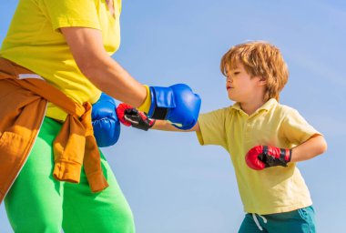 Adam oğlunu boks eğitiyor. Büyükbaba çocuk boks pozisyonunda duruyor. Dövüşçü. Kırmızı boks eldivenli küçük çocuğa koçluk yapan bir adam. Boks yapan küçük çocuk. Egzersiz yapıyor..