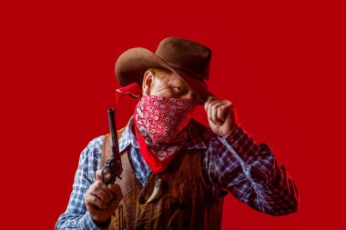 Maskeli Amerikalı haydut, şapkalı batılı adam. Kovboy şapkalı, silahlı, maço bir adamın portresi. Batı, silahlar. Şapkalı bir kovboy ya da çiftçi portresi. Bir kovboyun portresi.