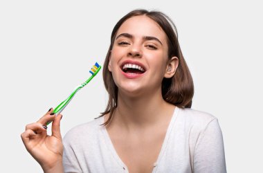 Diş fırçasıyla mükemmel ve sağlıklı dişler. Elinde diş fırçası tutan gülümseyen sevimli bir kadının portresi. Elinde diş fırçası tutan güzel dişleri olan gülümseyen bir kadın. Diş sağlığı geçmişi.