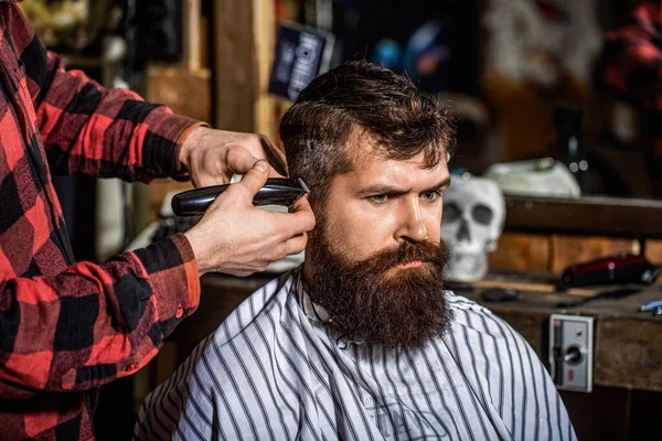 Berber saç makasıyla çalışıyor. Hipster müşteri saçını kestiriyor. Saç makasıyla berber elleri. Berber dükkanındaki sakallı adam. Berber dükkanında kuaförü ziyaret eden bir adam..