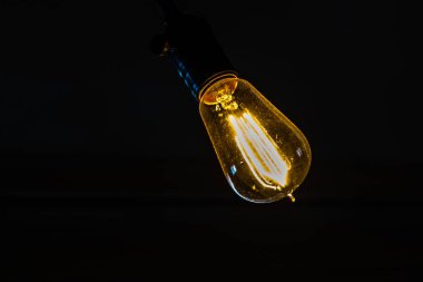 Edison ampul karşı siyah bir arka plan asılı.