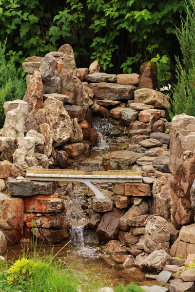 Miniature artificial stone waterfall with a bridge