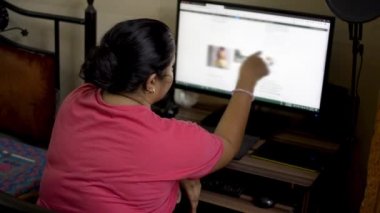 Evde masaüstü pc bilgisayar üzerinde çalışan pembe t-shirt Hint asya kafkas kadın. Ev hanımı masaüstü ekranında okuma internet sitesi blogu tarama. Yan görünüm kapalı çekimi kapat.   