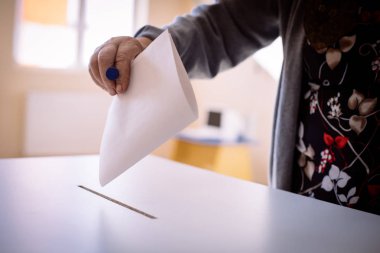 Seçimler sırasında sandık merkezinde oy kullanan bir kişinin renkli görüntüsü.