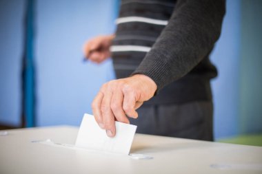Seçimler sırasında sandık merkezinde oy kullanan bir kişinin renkli görüntüsü.