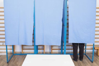 Seçimler sırasında, bir sandık merkezinde oy kullanan tanımlanamayan bir kişinin renkli görüntüsü.