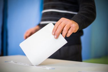 Color image of a person casting a ballot at a polling station, during elections. clipart