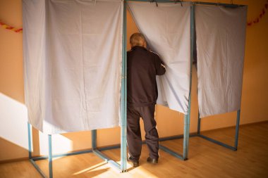 Seçimler sırasında, bir sandık merkezinde oy kullanan tanımlanamayan bir kişinin renkli görüntüsü.