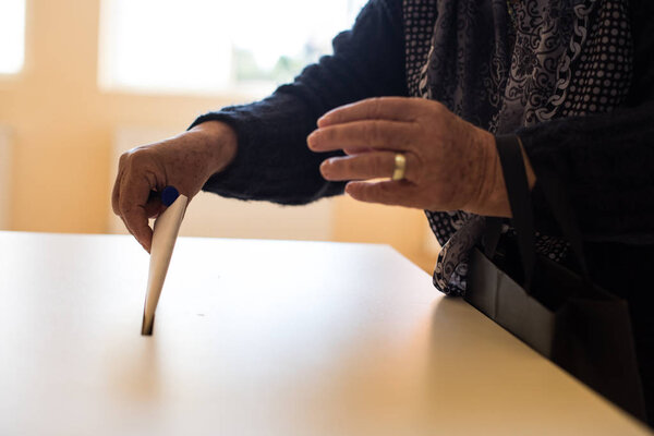 Color image of a person casting a ballot at a polling station, during elections.