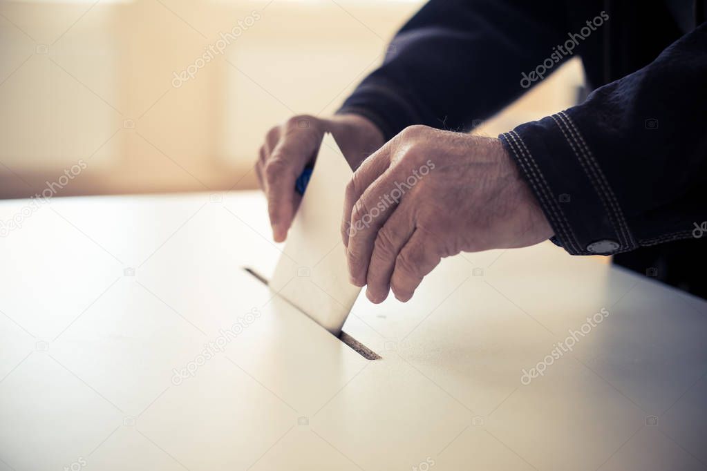 Color image of a person casting a ballot at a polling station, during elections.