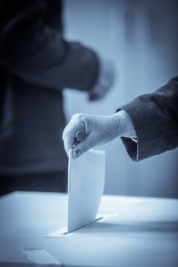 Seçimler sırasında sandık merkezinde oy kullanan bir kişinin renkli görüntüsü.