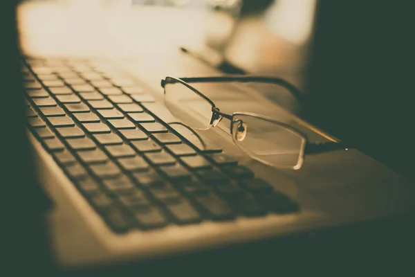 Coppia di occhiali su una tastiera di computer portatile — Foto Stock