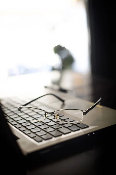 Coppia di occhiali su una tastiera di computer portatile — Foto Stock