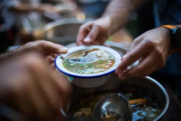 Persona que sirve una porción de sopa de pescado —  Fotos de Stock