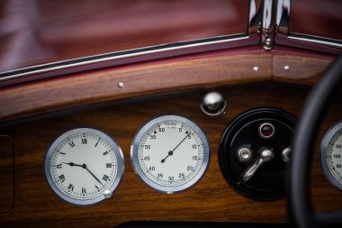 Eski bir arabanın gösterge panelinde takometre ve saat