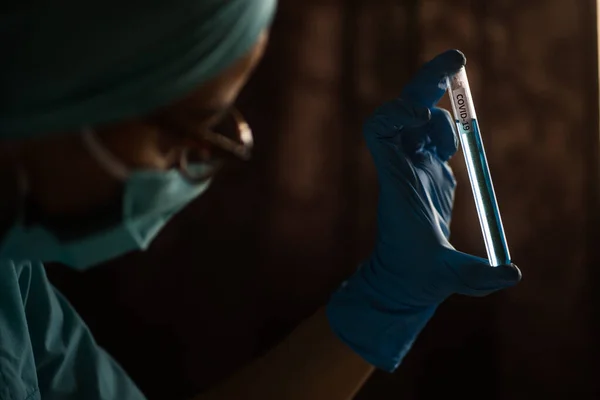 Close up image of a hand with glove handling a Covid-19 test tube, in a laboratory.