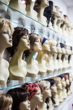 Saçı sıralanmış peruklar sergileniyor, bazı mankenlerde, bir mağazada..