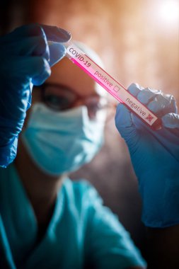 Coronavirus (COVID-19) için negatif örnekler içeren bir test tüpünü tutan ve gören bir doktorun kavramsal fotoğrafı).
