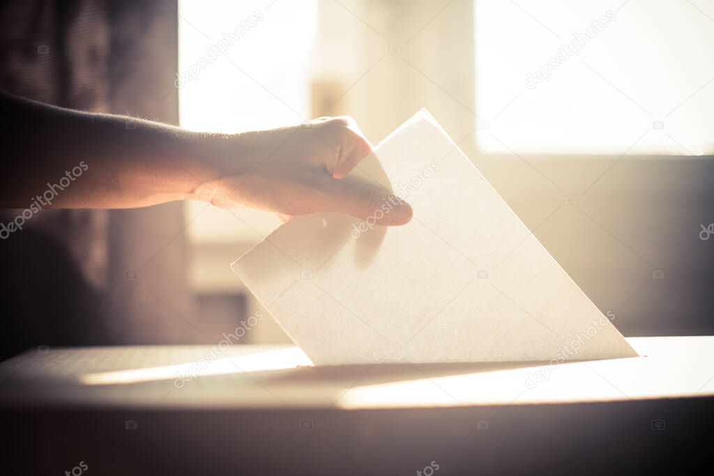 Conceptual image of a person voting, casting a ballot at a polling station, during elections.
