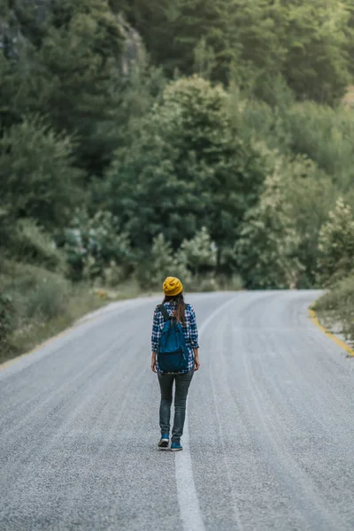 Concepto de viaje. Mujer viajera con mochila caminando por el campo de asfalto — Foto de Stock