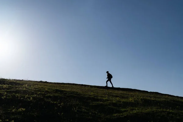 一个孤独的女子在日落时分走在一座小山的轮廓 — 图库照片
