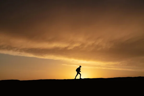 SIlhouette ของผู้หญิงที่โดดเดี่ยว เดินที่พระอาทิตย์ตกบนเนินเขา — ภาพถ่ายสต็อก