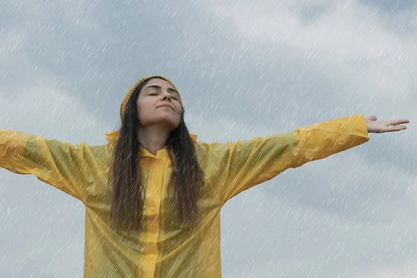 Donna che indossa un impermeabile giallo sotto la pioggia — Foto Stock