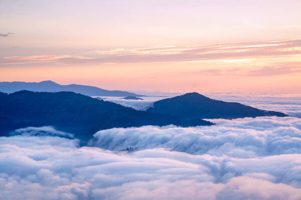 Mountain silhouette above the clouds at sunrise, view from the top view of mountains