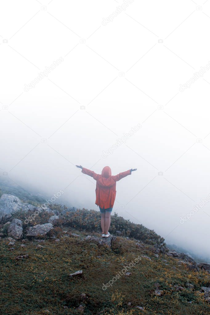 Cheering woman enjoy the beautiful view at misty mountain peak