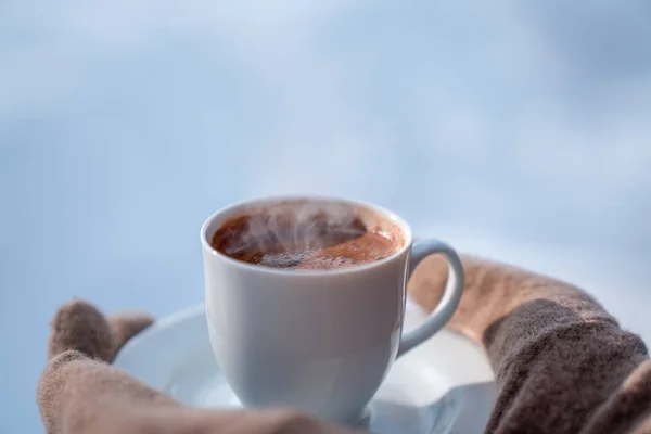 Main féminine dans des mitaines tenant tasse avec café chaud. Concept d'hiver . — Photo
