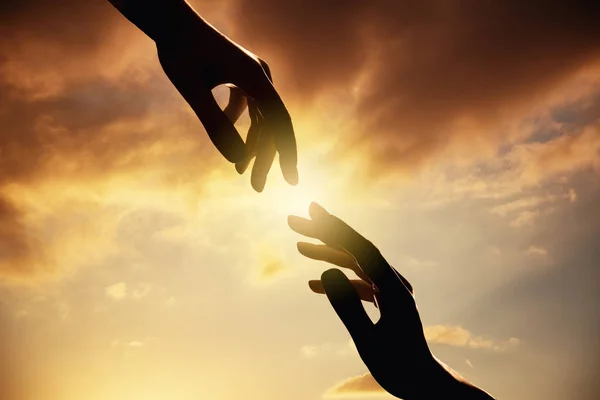 Sziluettjét az emberi kéz a naplemente. Bizalom és segítség koncepció. — Stock Fotó