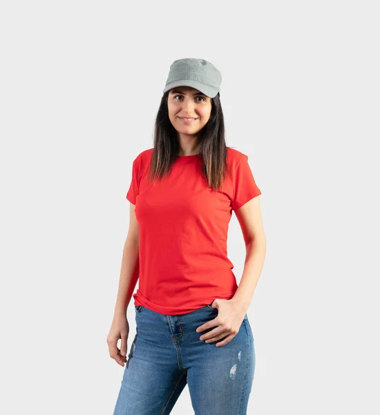빈 빨간 티셔츠를 입고 모자와 청바지를 입은 소녀. 회색 벽 배경 — 스톡 사진