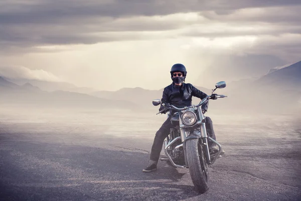 Vedere laterală a unui tânăr motociclist care stă pe marginea drumului împotriva apusului de soare în timp ce călătorește cu bicicleta . — Fotografie, imagine de stoc