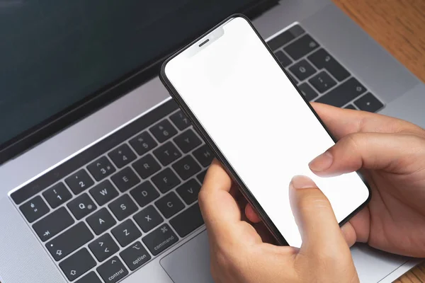 Hombre sosteniendo el teléfono inteligente sobre el ordenador portátil con pantalla en blanco. concepto de publicidad de tecnología —  Fotos de Stock