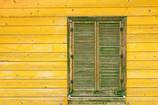 古老的黄色木墙，有绿色的窗户。房屋装饰. — 图库照片
