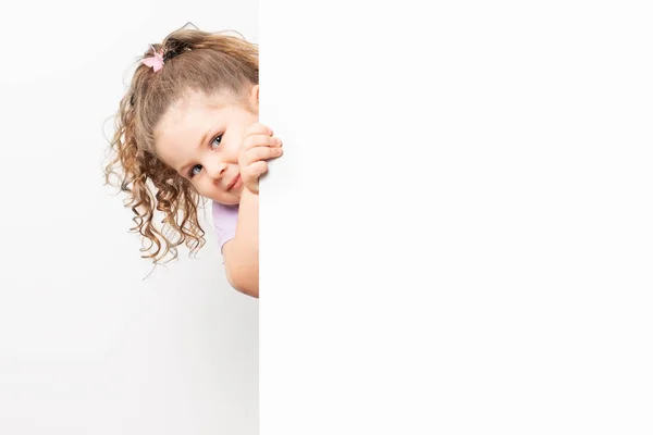 Sonriente niña de ojos azules asomándose detrás de una pizarra blanca —  Fotos de Stock