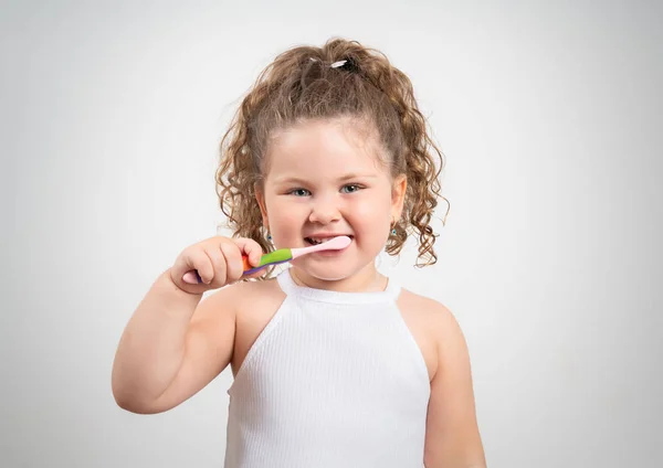 Linda chica rubia cepillándose los dientes sobre un fondo blanco aislado . —  Fotos de Stock