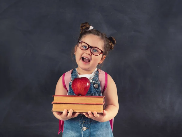 Pequeño niño lindo sosteniendo libros en pizarra.Concepto de educación . — Foto de Stock