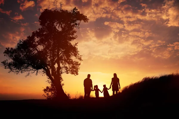 Gelukkig familie silhouet staande op tegen zonsondergang tijd — Stockfoto