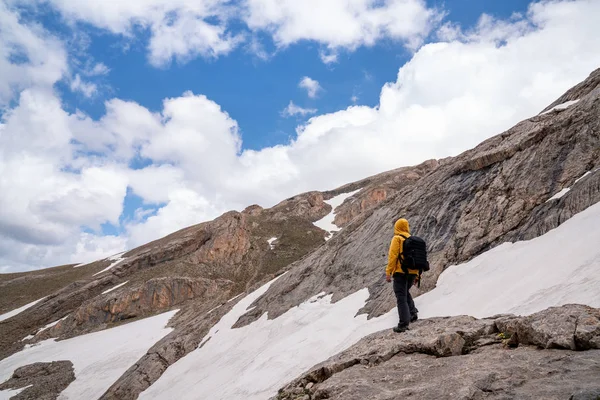 Hiker Żółtym Płaszczem Przeciwdeszczowy Stojący Skale Przed Śnieżną Górą — Zdjęcie stockowe