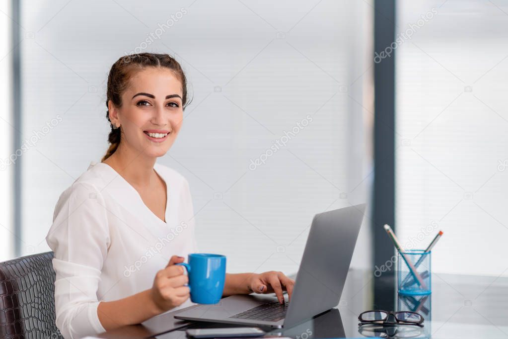 Young business woman enjoying coffee break at office
