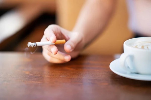 Junge Frau raucht und hält eine Tasse Kaffee in einem Café — Stockfoto