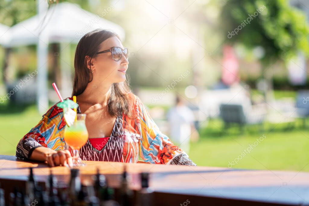 Young woman relaxing and drinking some beverage on the bar on a vacation