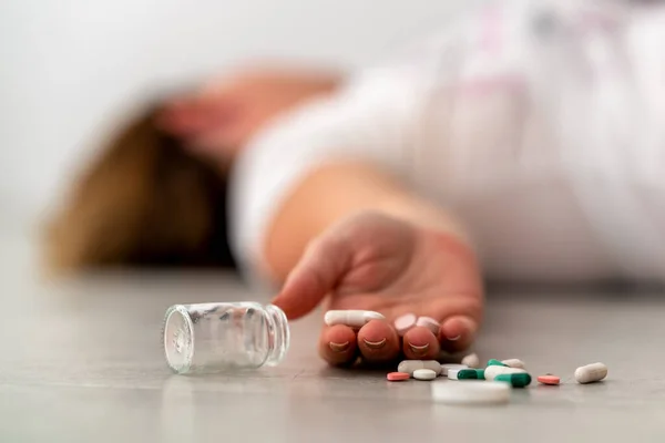 Przedawkowanie i leżenie na podłodze z tabletkami. — Zdjęcie stockowe
