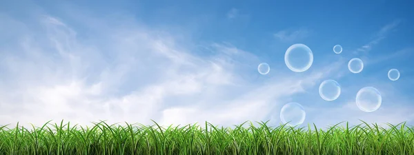 Many soap bubbles landing on the green lawn with a cloudy blue panoramic sky background. — Stock Photo, Image