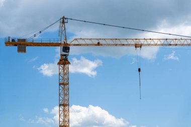 Mavi ve bulutlu gökyüzüne karşı inşaat vinci olan bir bina..